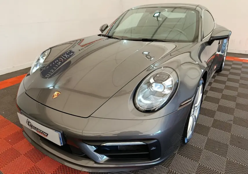 Vue 3/4 avant d'une Porsche 911 Carrera 4S Coupé gris foncé avec phares LED et jantes argentées.