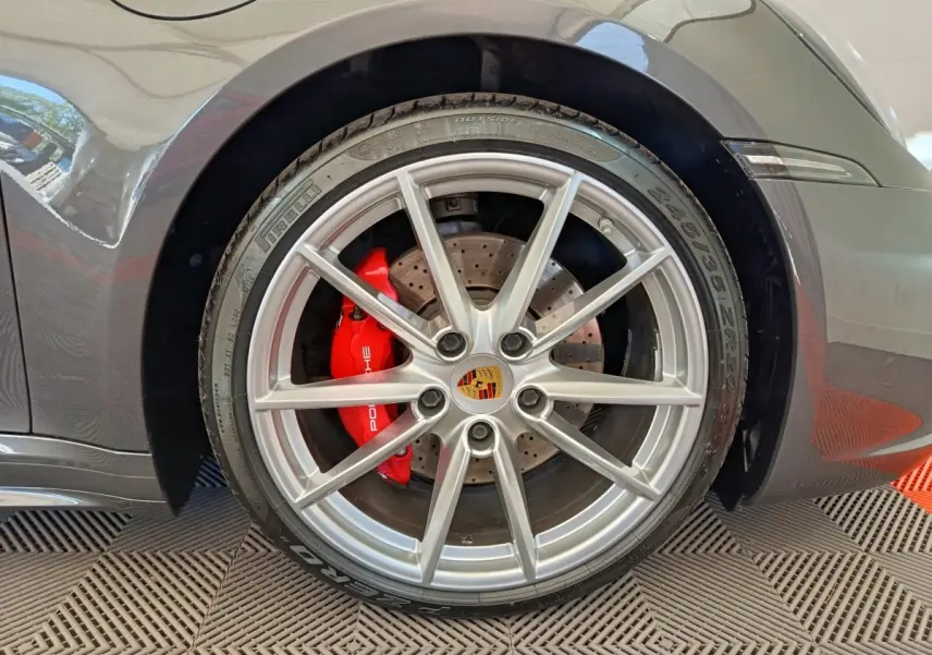 Gros plan sur la roue arrière droite gris foncé d'une Porsche 911 Carrera 4S avec étrier de frein rouge et jante argentée.