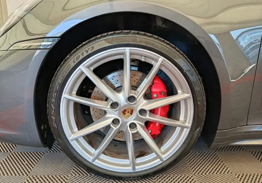 Gros plan sur la roue avant droite grise d’une Porsche 911 Carrera 4S avec étrier de frein rouge visible.