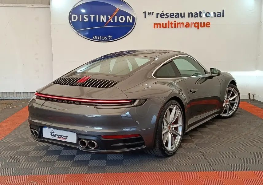 Vue 3/4 arrière droite d'une Porsche 911 Carrera 4S Coupé gris foncé avec feux arrière LED et quadruple sortie d'échappement.