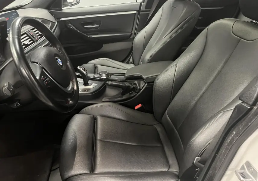 Vue intérieure côté conducteur de la BMW Série 4 430i Gran Coupé 2019 avec sellerie cuir noire et volant multifonctions.