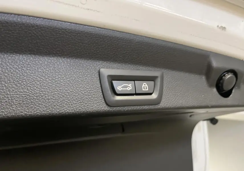 Boutons de fermeture électrique du hayon sur intérieur de coffre d'une BMW Série 4 blanc vue rapprochée.