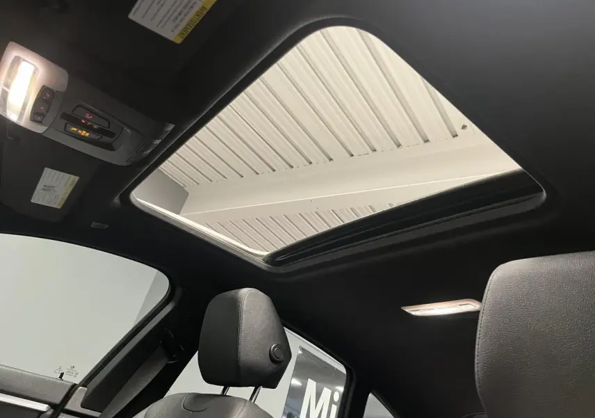 Vue intérieure du toit ouvrant en verre électrique du BMW Série 4 Gran Coupé 430i, avec sellerie cuir noire et éclairage intérieur.