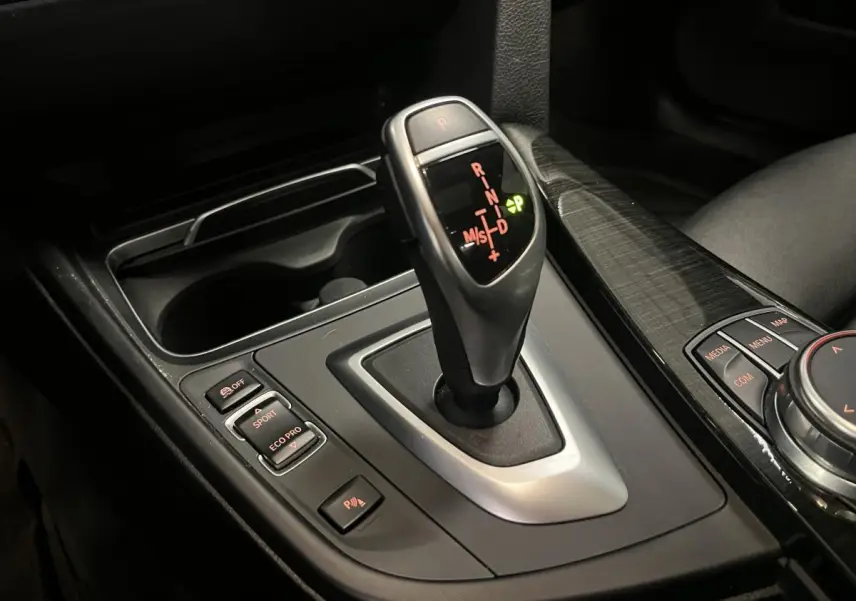 Le levier de vitesses automatique de la BMW Série 4 430i Gran Coupé, entouré de commandes de mode de conduite et d'un habillage noir brillant.