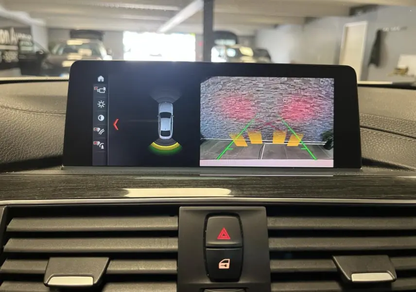 Affichage écran intérieur de BMW Série 4 blanc 2019 montrant caméra de recul et capteurs de stationnement.