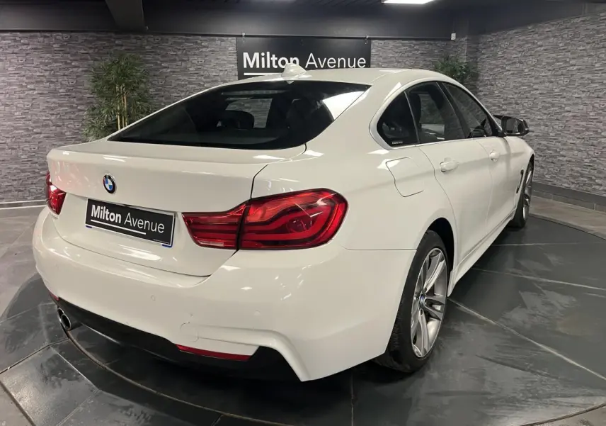 BMW Série 4 430i Gran Coupé blanc vue 3/4 arrière droit avec jantes alliage 18'' et feux arrière LED rouges.