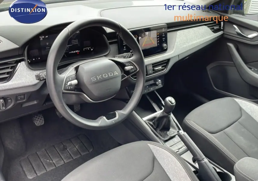 Intérieur avant de la Skoda Scala 2025, vue côté conducteur, volant cuir, tableau de bord gris et écran tactile.