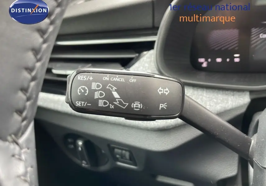 Gros plan sur la commande de régulateur de vitesse à gauche du volant d’une Skoda Scala noir magique métal, intérieur gris.
