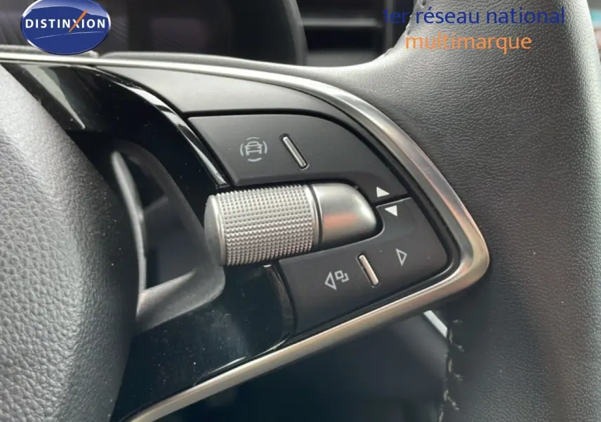 Gros plan sur les commandes multifonctions en métal brossé du volant cuir noir de la Skoda Scala 2025.