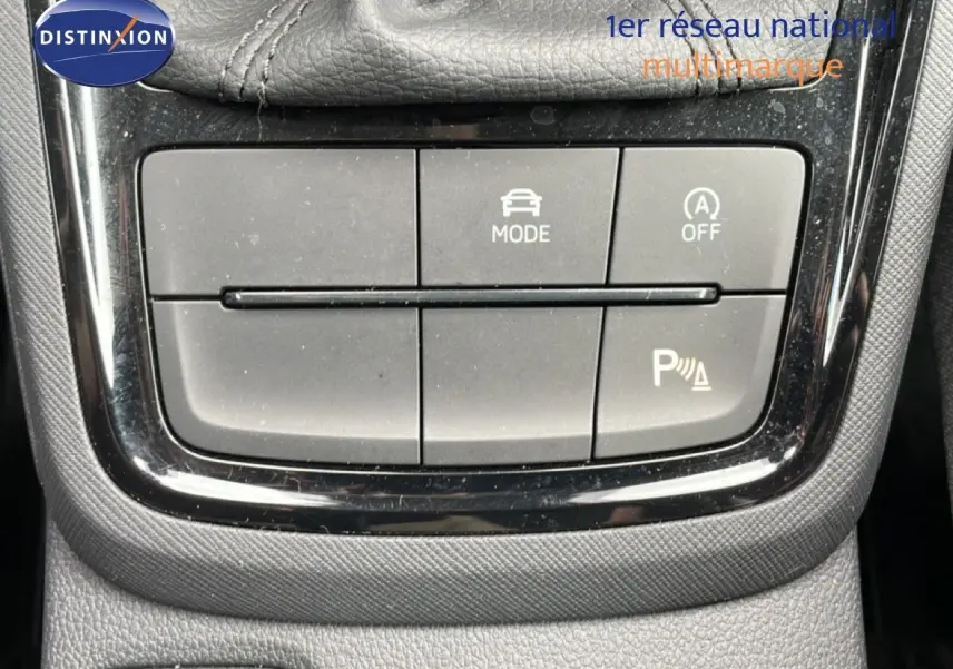 Gros plan sur les boutons de commande du mode de conduite et assistance au stationnement d'une Skoda Scala noire.