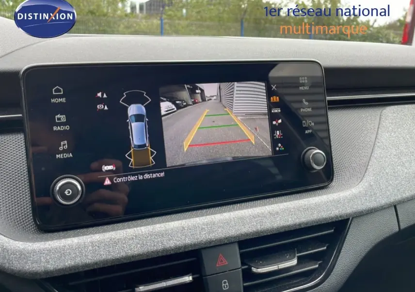 Écran central affichant la caméra de recul et l'alerte de distance dans un Skoda Scala noir Magic Metal, vue intérieure.