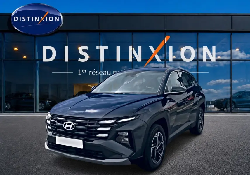 Hyundai Tucson 1.6 t-gdi 239 hybride gris ecotronique vu en 3/4 avant devant un bâtiment vitré Distinxion.