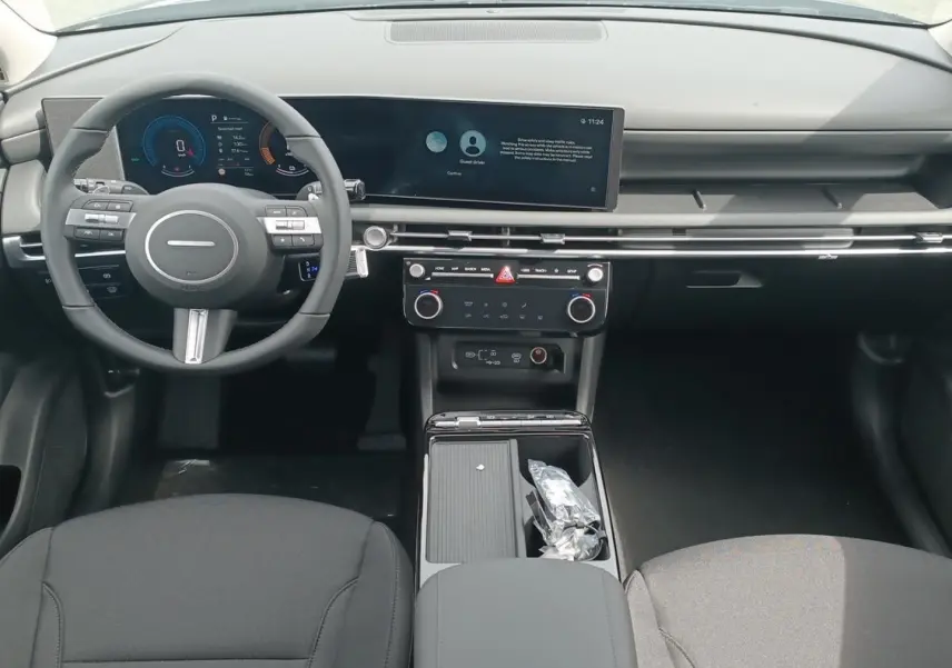 Vue intérieure avant du Hyundai Tucson 2026, tableau de bord moderne avec écran large et volant multifonction noir.