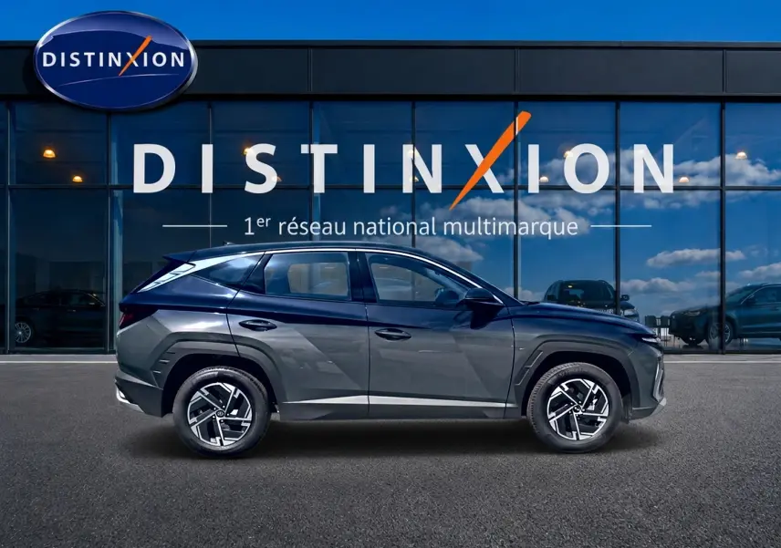 Vue de profil côté gauche du Hyundai Tucson 1.6 t-gdi 239 hybride gris ecotronique devant une vitrine Distinxion.