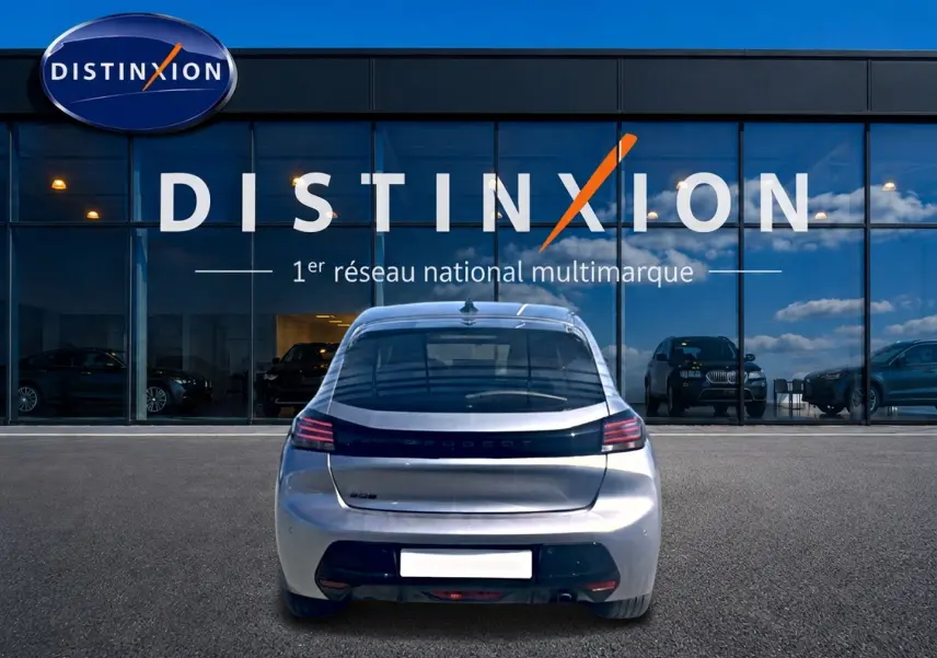 Vue arrière d'une Peugeot 208 gris artense 2025, garée devant une vitrine avec logo Distinxion en arrière-plan.