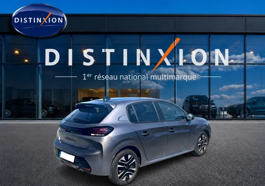 Peugeot 208 1.2 100 Allure gris Artense vue 3/4 arrière droit devant un showroom Distinxion.