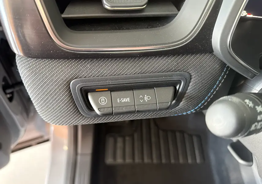 Gros plan sur les commandes E-SAVE et réglage des phares sur la console inférieure côté gauche du Renault Captur Gris Rafale.