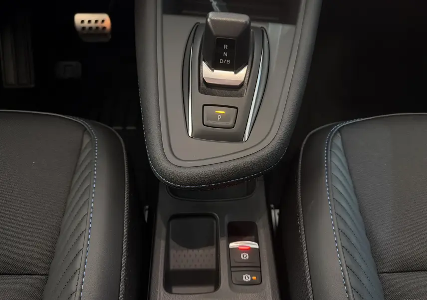 Vue rapprochée de la console centrale du Renault Captur E-Tech 160 Esprit Alpine avec levier de vitesse et sellerie noire à surpiqûres bleues.
