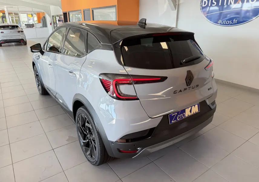 Vue 3/4 arrière droite du Renault Captur E-Tech 160 Esprit Alpine gris Rafale avec toit noir et jantes noires en showroom.