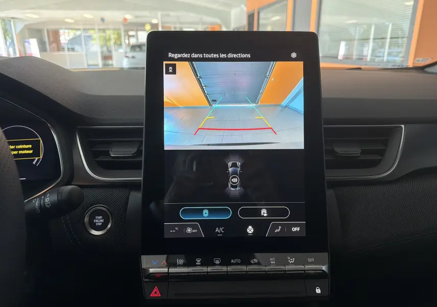 Vue intérieure centrée sur l'écran tactile affichant la caméra de recul du Renault Captur gris Rafale, tableau de bord et commandes visibles.