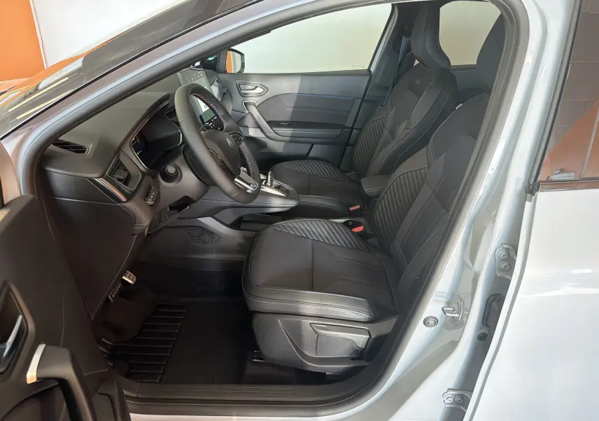 Vue intérieure côté conducteur du Renault Captur E-Tech 160 Esprit Alpine 2026, sièges noirs avec surpiqûres bleues et logo Alpine.
