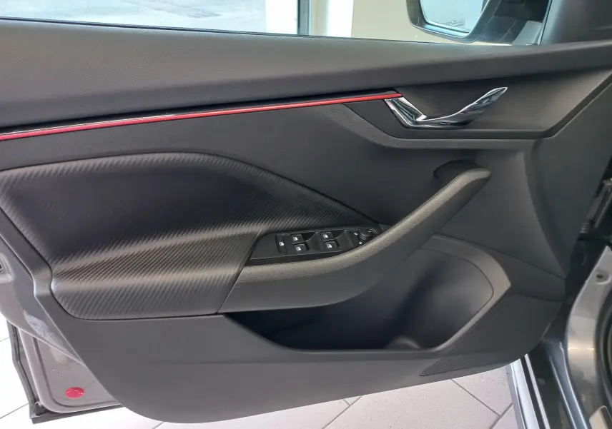 Intérieur côté gauche de la porte Skoda Kamiq Monte Carlo 2024 gris graphite avec insert carbone et bande rouge décorative.