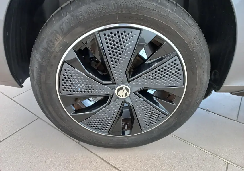 Gros plan sur la roue avant droite du Skoda Kamiq 2024 gris graphite, avec jante Monte Carlo noire et grise à motifs perforés.