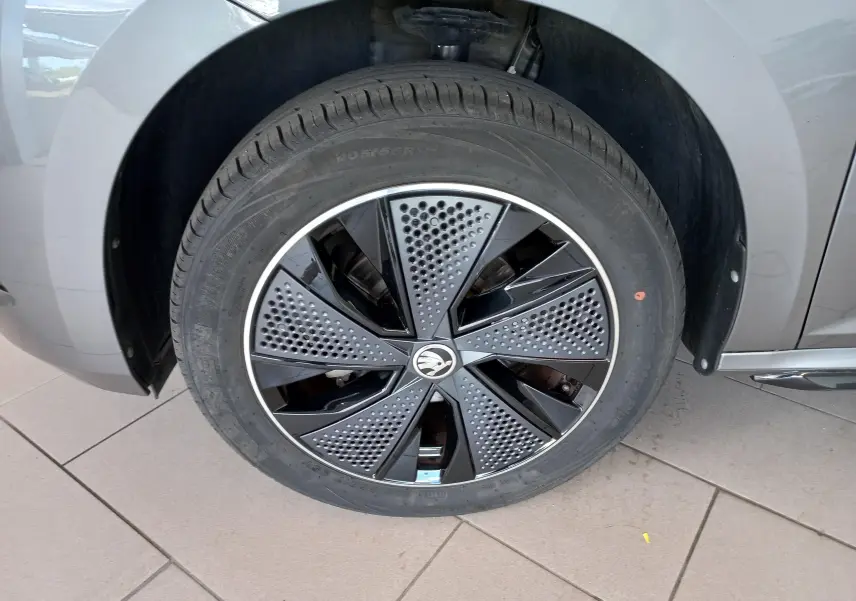 Gros plan sur la roue avant droite du Skoda Kamiq 2024 gris graphite avec jante Monte Carlo au design perforé noir et argent.