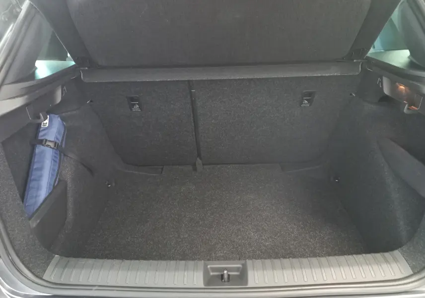Coffre ouvert vu de l'arrière du Skoda Kamiq 1.5 TSI Monte Carlo gris graphite, montrant un espace de rangement propre.