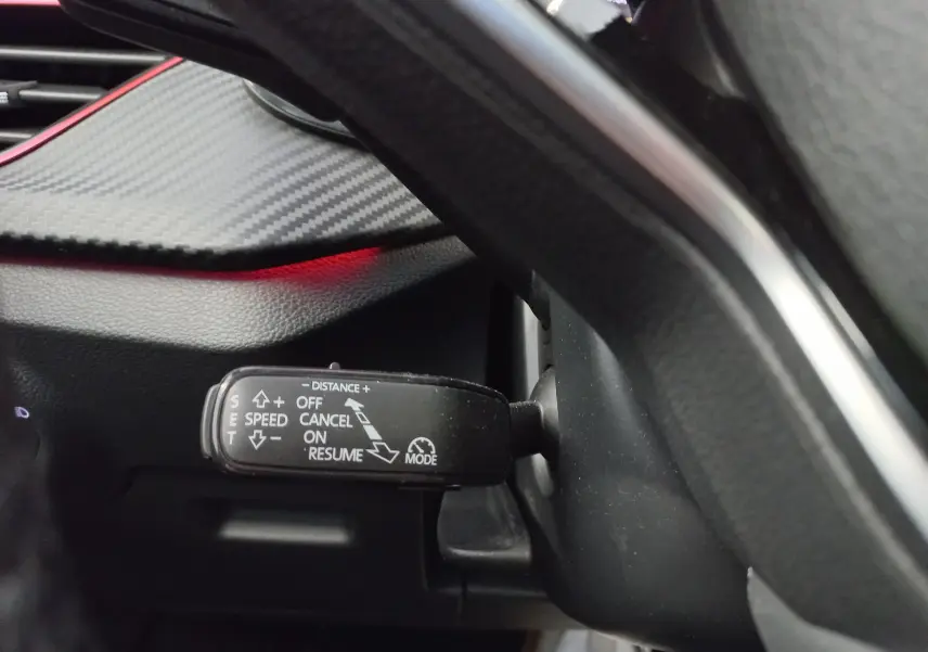 Gros plan sur la commande de régulateur de vitesse du Skoda Kamiq 1.5 TSI 150 DSG7 Monte Carlo, intérieur noir avec insert carbone.