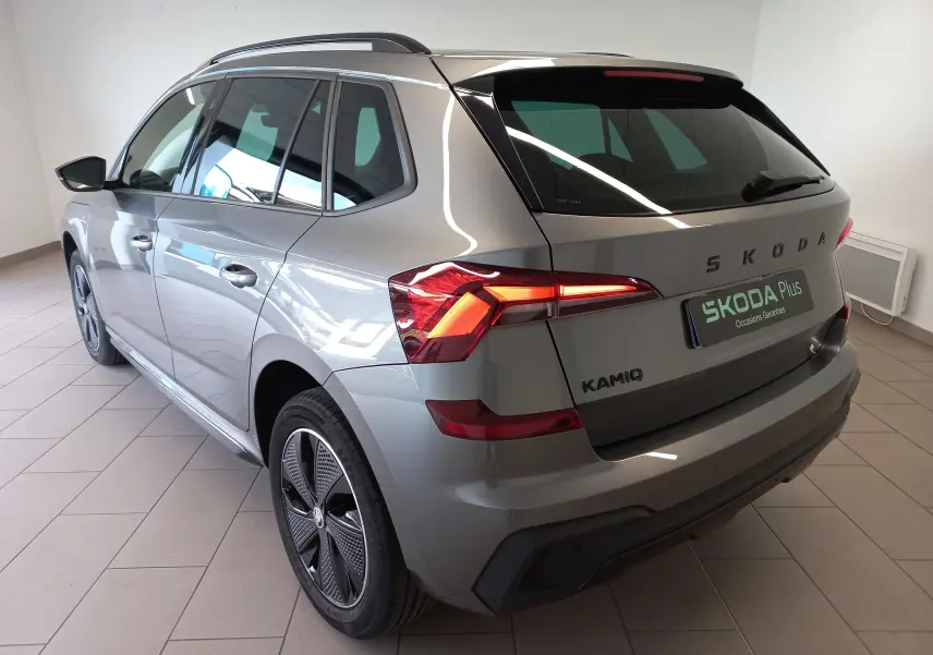 Vue 3/4 arrière droite d’un Skoda Kamiq 2024 gris graphite avec feux arrière allumés et jantes spécifiques Monte Carlo.
