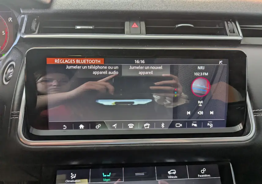 Écran tactile central du Range Rover Velar noir 2020 affichant les réglages Bluetooth et la radio NRJ.