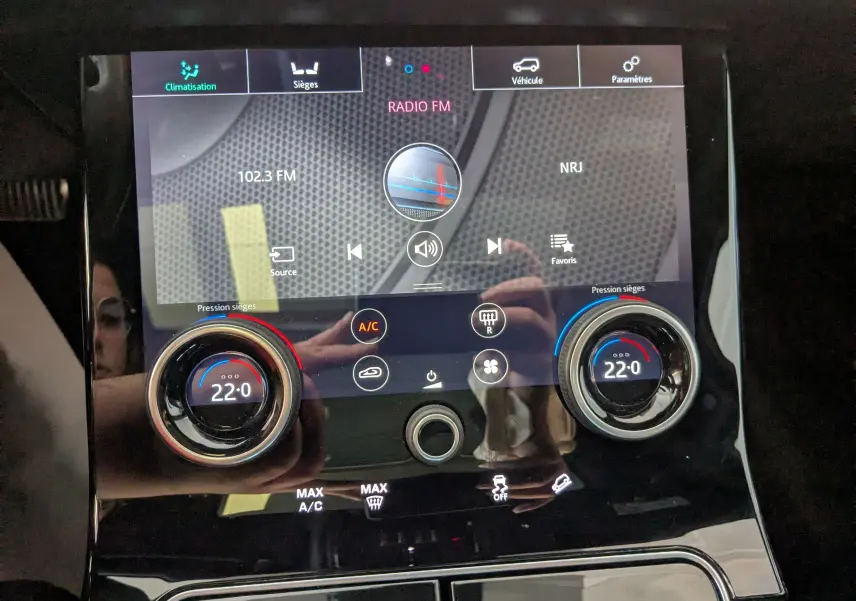 Écran tactile central du Range Rover Velar noir 2020 montrant la radio FM et les réglages de climatisation à 22°C.