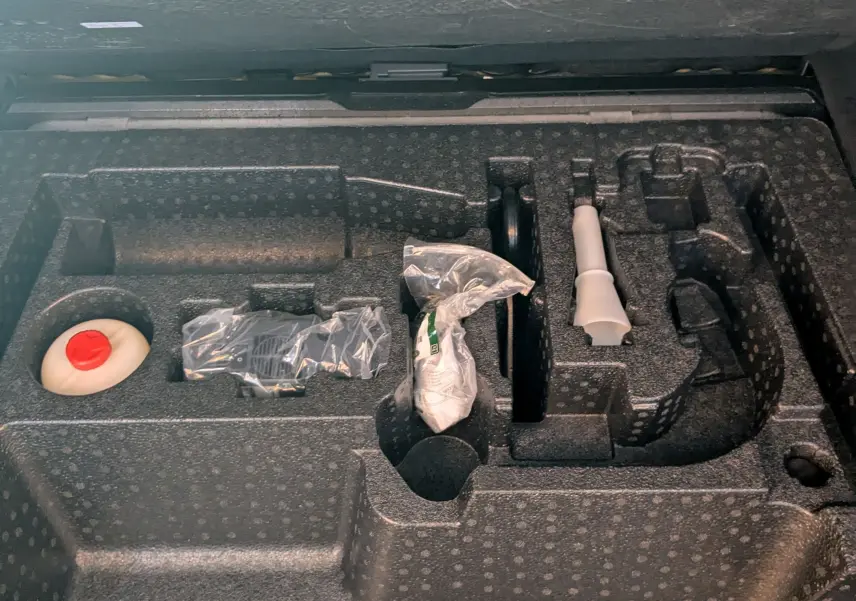 Compartiment de rangement sous le coffre du Range Rover Velar noir, montrant les outils et accessoires d'origine.