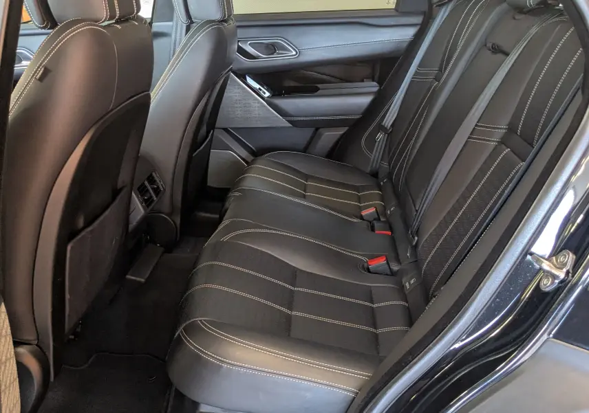 Vue côté droit de l'habitacle arrière noir du Range Rover Velar 2020 avec sièges en cuir et surpiqûres contrastées.