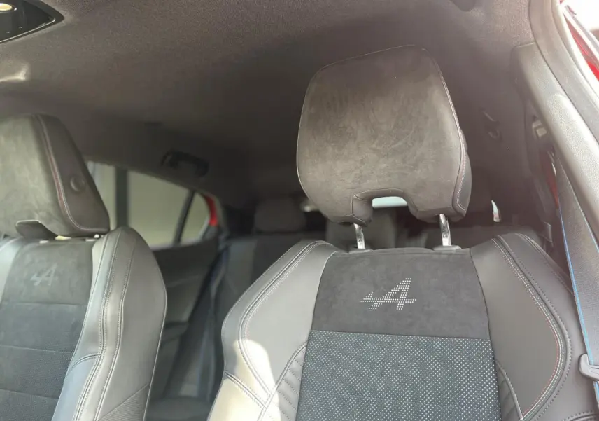 Gros plan sur les sièges avant noirs de la Renault Rafale Esprit Alpine avec logo "A" lumineux et surpiqûres tricolores.