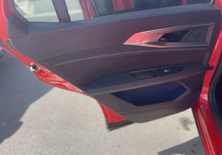 Gros plan sur la porte arrière gauche rouge du Renault Rafale 2025 avec garniture noire et surpiqûres blanches.