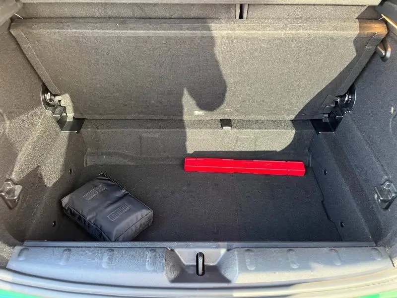 Coffre ouvert d'une MINI Cooper S 2021 British Racing Green, montrant un rangement noir avec triangle de signalisation rouge.