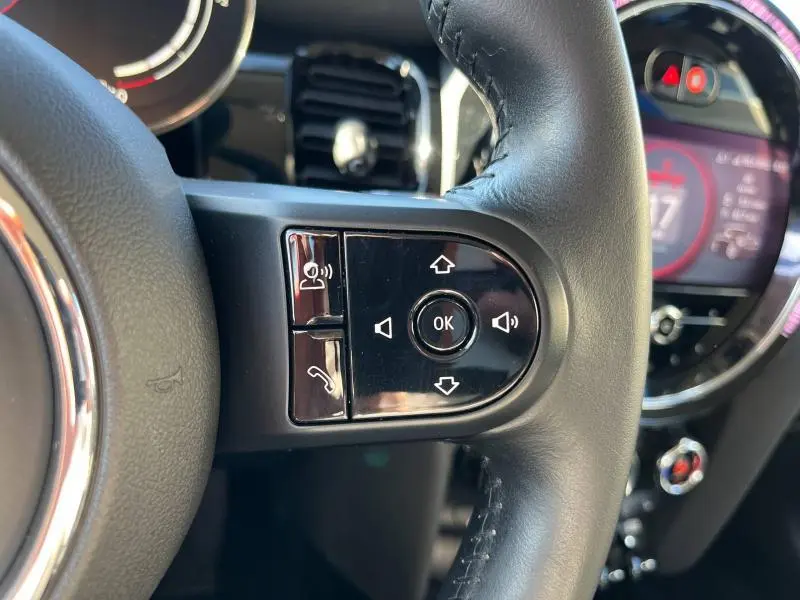 Gros plan sur les commandes multifonctions à droite du volant cuir noir d'une MINI Cooper S British Racing Green 2021.