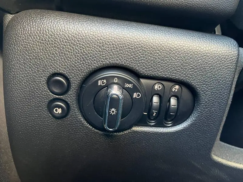 Gros plan sur les commandes d'éclairage noires en plastique texturé dans l'habitacle du MINI Cooper S 2021.