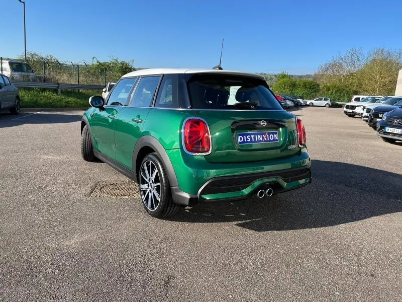 Vue 3/4 arrière droite d'une MINI Cooper S 2021 British Racing Green avec toit blanc et double sortie d'échappement chromée.