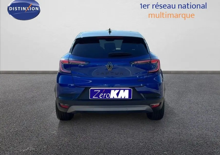 Vue arrière du Renault Captur E-Tech hybride bleu Iron Metal avec toit noir, immatriculé Zero KM, sur sol gris.