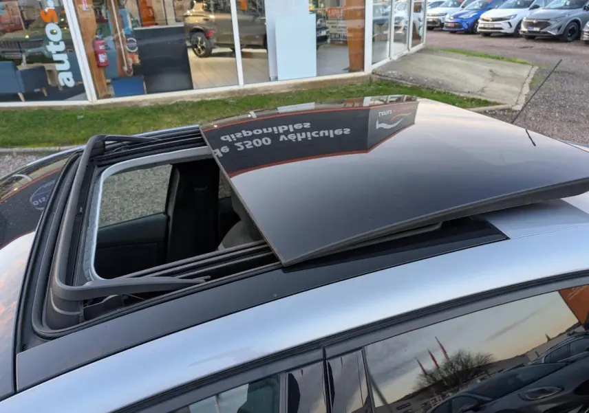 Toit ouvrant vitré ouvert vu de dessus sur une Citroën C4 gris métallisé stationnée en extérieur.