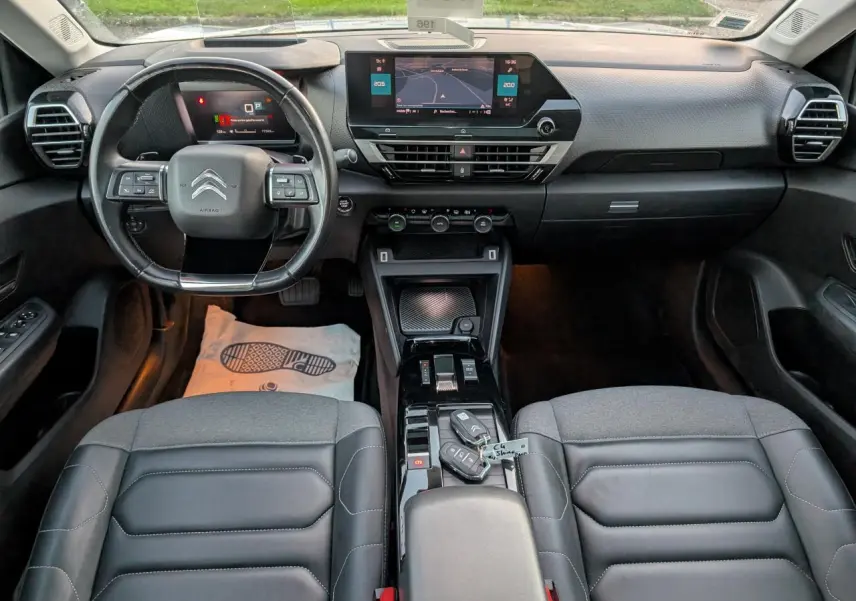 Vue intérieure avant du poste de conduite de la Citroën C4 Shine 2022 avec sièges cuir noir et écran tactile central.