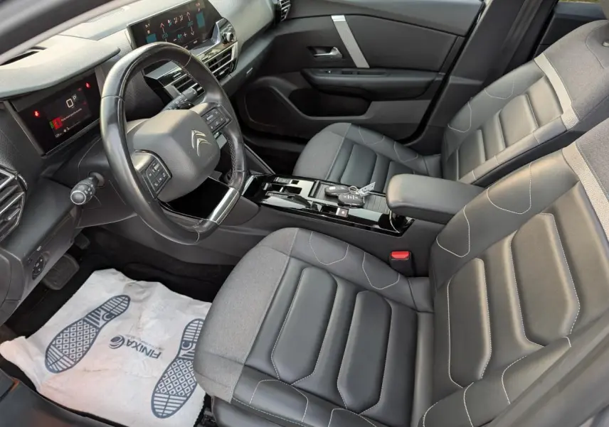 Vue intérieure côté conducteur de la Citroën C4 gris, avec sièges cuir/textile noirs et console centrale brillante.