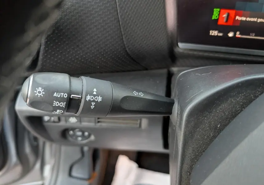 Gros plan sur la manette de clignotants et feux à gauche du volant dans l’habitacle du Citroën C4 gris 2022.
