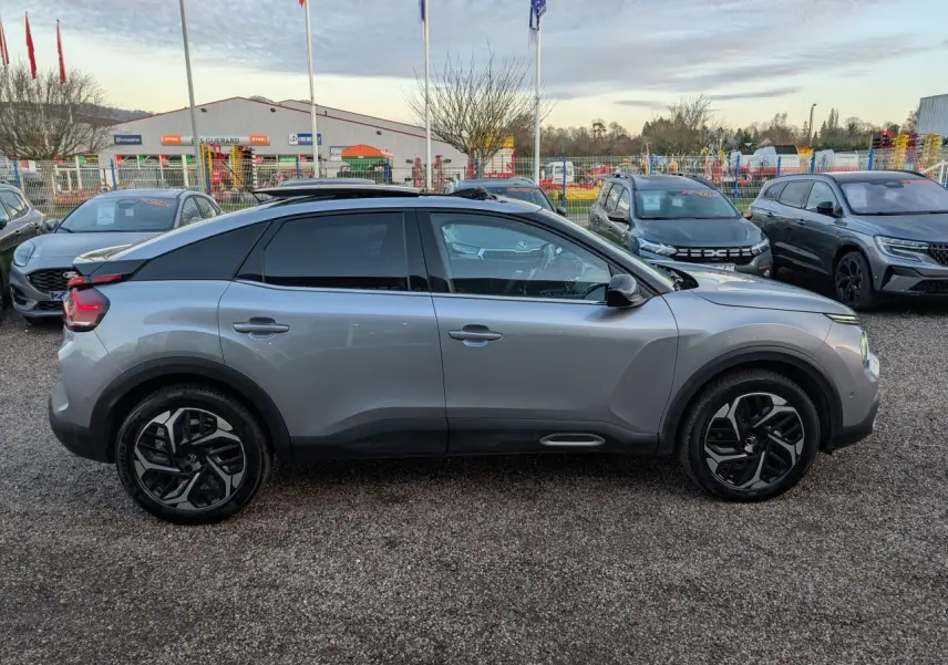 Profil côté gauche d'une Citroën C4 gris métallisé 2022 avec toit ouvrant et jantes alliage noires.