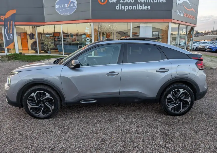 Vue de profil côté gauche d'une Citroën C4 gris métallisé avec jantes alliage et toit ouvrant vitré.