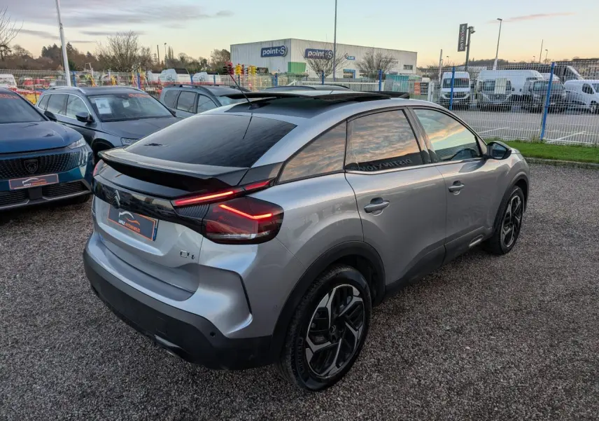 Vue 3/4 arrière droite d'une Citroën C4 gris métallisé avec toit ouvrant vitré et feux arrière LED en V.