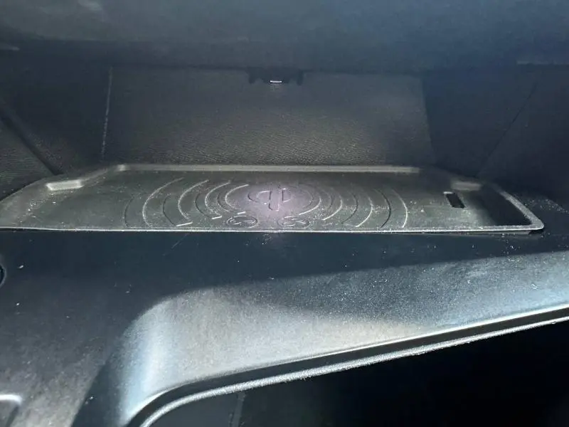 Gros plan sur le compartiment de recharge sans fil noir dans l'habitacle de la Peugeot 308 gris Artense.
